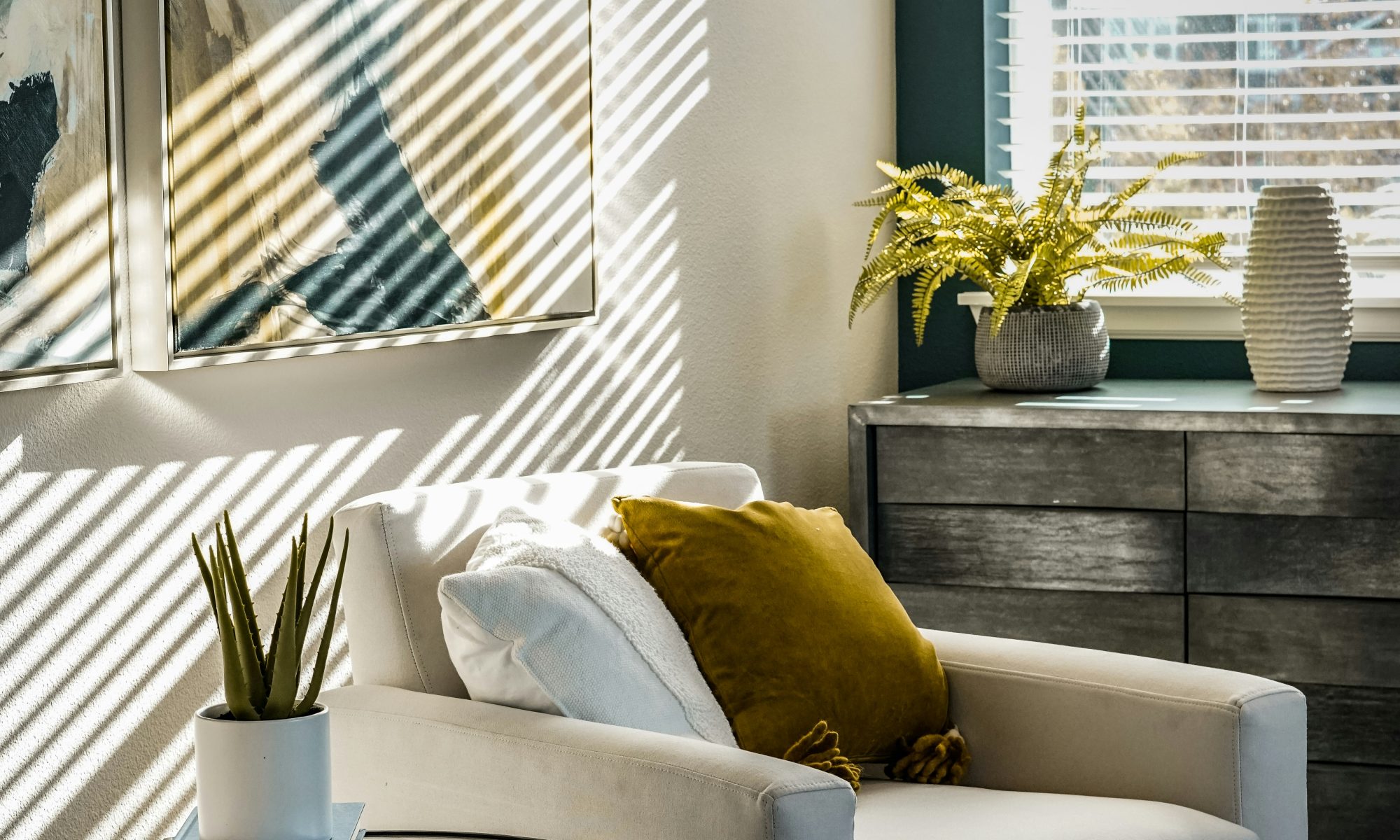 contemporary living space, two cream arm chairs with coffee table in middle. Modern art on walls and light coming in from window. Calm but upbeat energy, suggestive of the type of therapy you can expect from this company