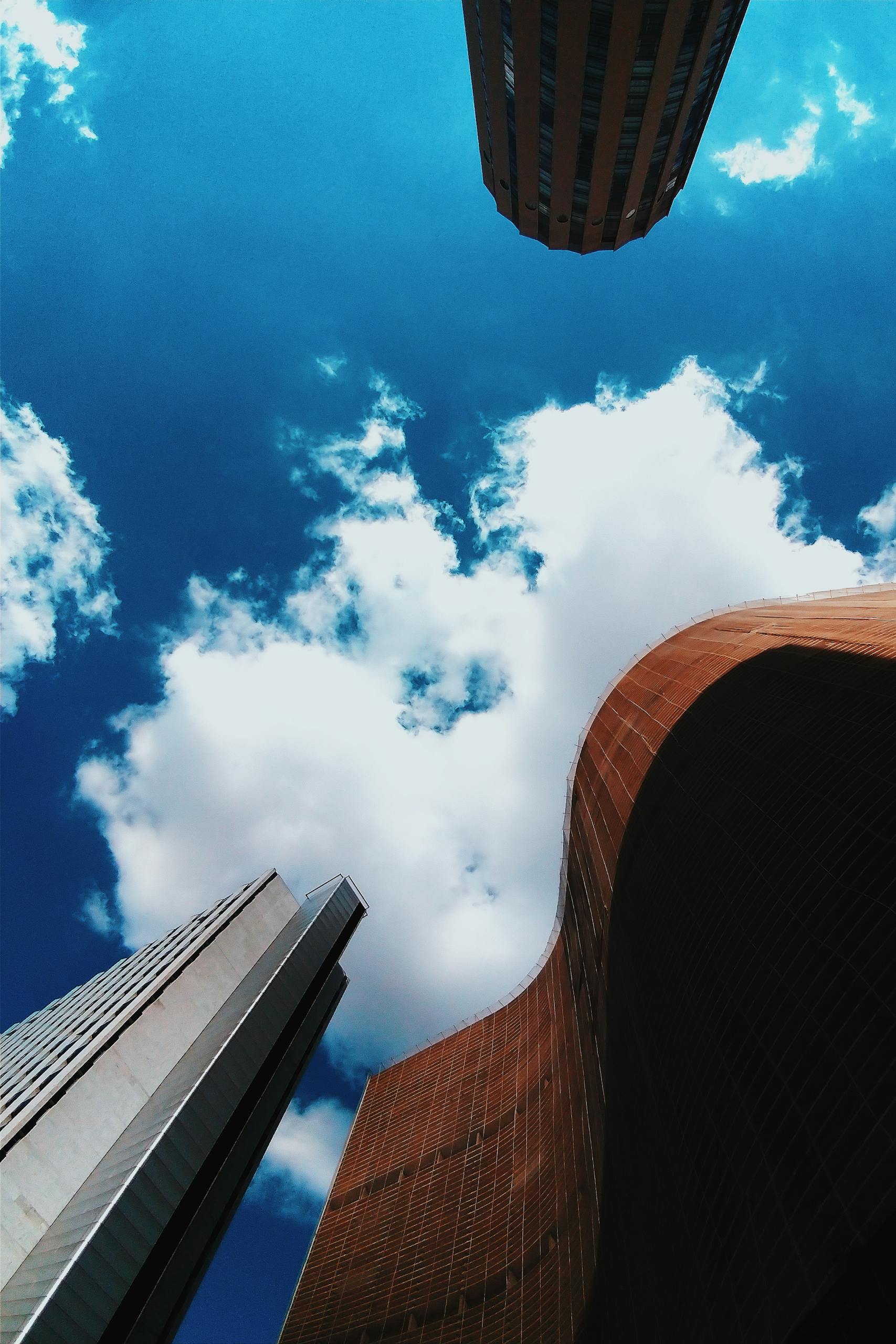 Low angle view of modern skyscrapers against a vibrant blue sky with clouds in Itinga, MT, Brazil.
